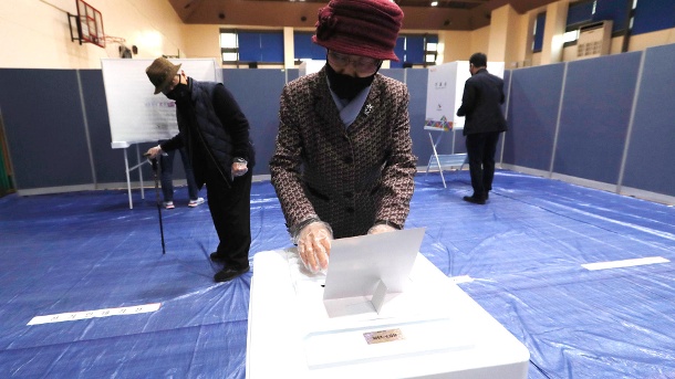 Parlamentswahl in Südkorea: Eine Frau trägt aufgrund des neuartigen Coronavirus eine Maske und gibt in einem Wahllokal ihre Stimme ab. (Quelle: Ahn Young-Joon/AP/dpa)