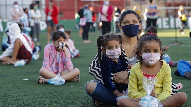 Eine Familie sitzt auf einem Fußballfeld in der Favela Paraisopolis in Sao Paulo: Die Neuinfektionen in dem lateinamerikanischen Land steigen weiter rasant an. (Quelle: Andre Penner/AP/dpa)